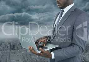 Businessman on laptop with city background