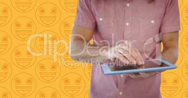 Man pink shirt mid section with tablet against yellow emoji pattern