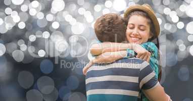 Happy woman with eyes closed hugging man over bokeh