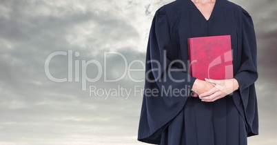 Judge holding book in front of sky clouds
