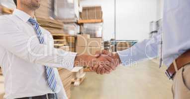 Midsection of businessmen doing handshake in warehouse
