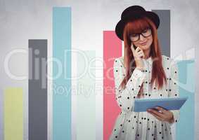 Woman in hat with tablet against colourful graphs against white wall