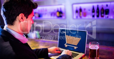 Businessman using laptop with shopping cart on screen
