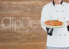Chef showing the pizza. Blurred wood background