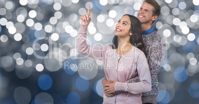 Man embracing woman pointing against blur background