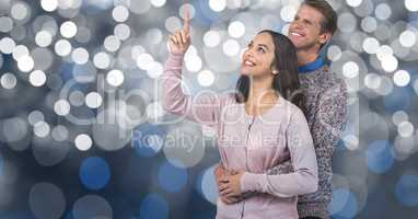 Man embracing woman pointing against blur background