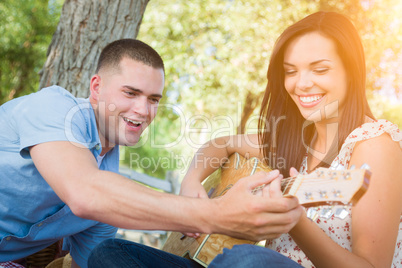 Handsome Young Man Teaching Mixed Race Girl to Play Guitar at th