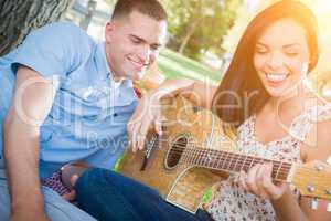 Happy Mixed Race Couple at the Park Playing Guitar and Singing S