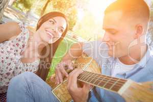 Happy Mixed Race Couple at the Park Playing Guitar and Singing S