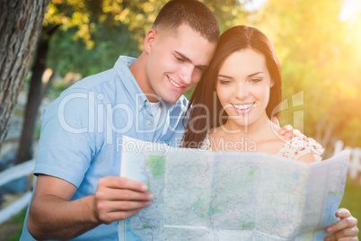 Happy Mixed Race Couple Looking Over A Map Outside Together.