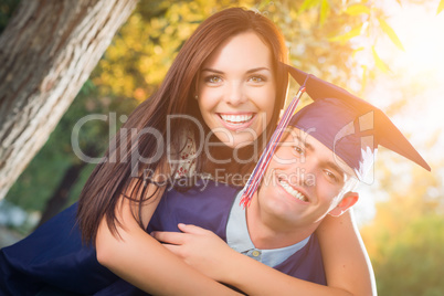 Happy Male Graduate in Cap and Gown and Pretty Girl Celebrate Ou