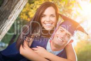 Happy Male Graduate in Cap and Gown and Pretty Girl Celebrate Ou