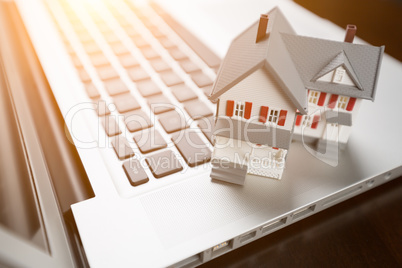 Miniature House And Laptop Computer Resting on Desktop.