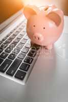 Piggy Bank Resting on Laptop Computer Keyboard.