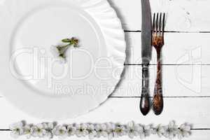 White empty plate with cutlery on a wooden surface