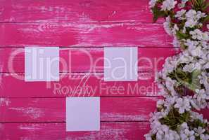 Three blank white sheets on a pink wooden surface