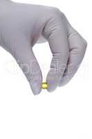 Hand in latex glove holding a pill
