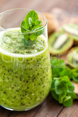Fresh green kiwi smoothie with mint and honey, healthy organic drink on wooden table