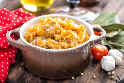 Stewed cabbage with meat on dark rustic wooden background