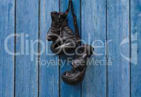 Black vintage boxing gloves hanging on an old rusty nail