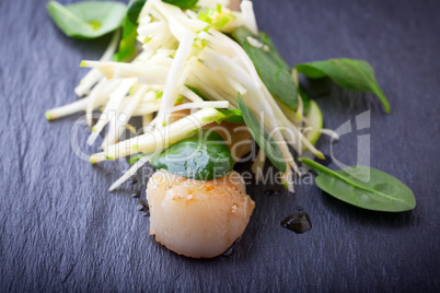 Scallop salad with apple, spinach on a stone plate.