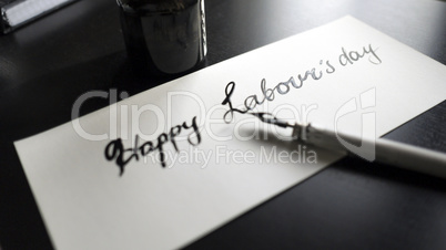 Happy labour's day calligraphy and lattering post card. Left view with calligraph pen.