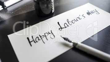 Happy labour's day calligraphy and lattering post card. Left view with calligraph pen.