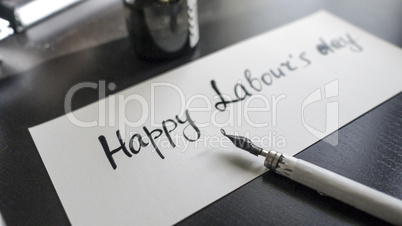 Happy labour's day calligraphy and lattering post card. Left view with calligraph pen.