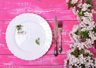 White dish with an empty paper note on a pink wooden surface