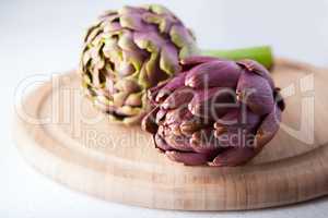 Two artichokes lying on a wooden plate
