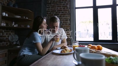 Cheerful couple sharing orange juice in kitchen
