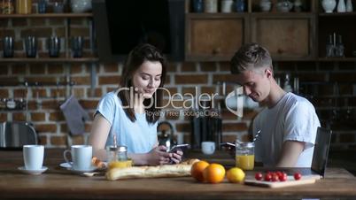 Couple eating breakfast whilst using mobile phones