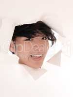 Asian man looking trough hole in paper.