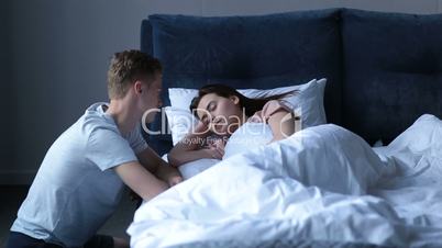 Handsome man gently waking woman in the morning