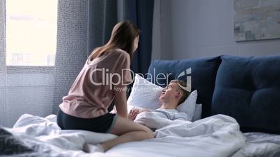 Playful woman waking up his sleepy man in morning