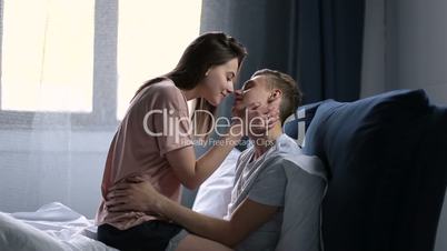 Loving couple on bed in affectionate sensual kiss