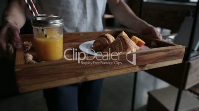 Delicious breakfast on wooden tray served by man