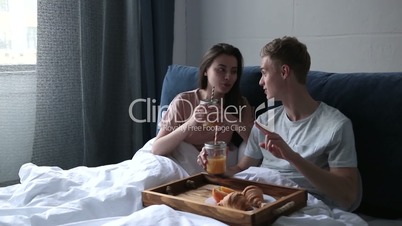 Young couple enjoying romantic breakfast in bed