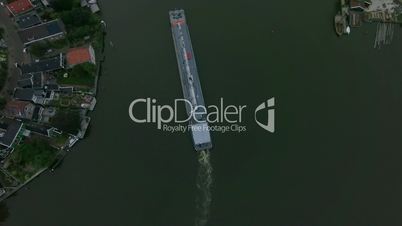 Aerial shot of barge sailing down the river in town
