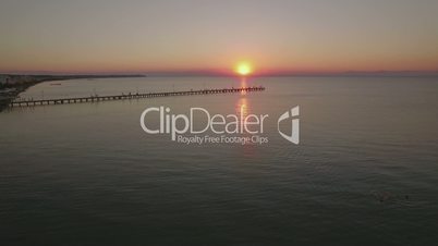 Flying over sea and pier at sunset