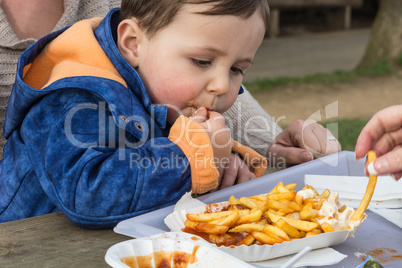 Kind ißt Curry Wurst mit Pommes friets
