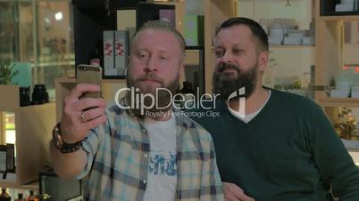 Two bearded men taking mobile selfie indoor