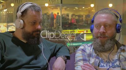 Two bearded men listening to music in headphones