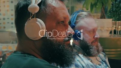 Bearded men in headphones enjoying music