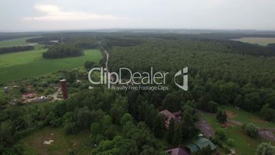 Aerial flight above the Lukino, Moscow, picturesque landscape of green forest and fields, countryside buildings and traffic