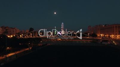 Aerial night view of lighted ferris wheel and bridge against sky with moon , Valencia, Spain