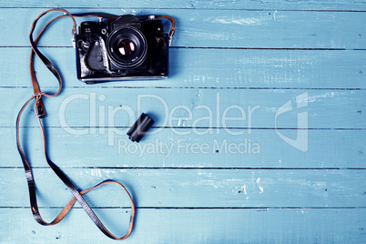 Vintage film camera in a leather case on a blue wooden surface