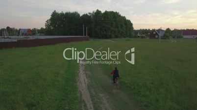 Aerial steadicam view of boy riding a bike at summer, Russia