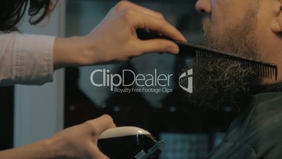 Close up view of woman hands cares of beard. Barber combing and trimming beard