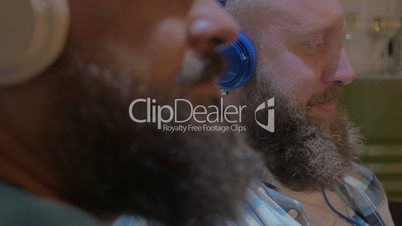 Close up view of two bearded men listening musics using colorful on-ear headset
